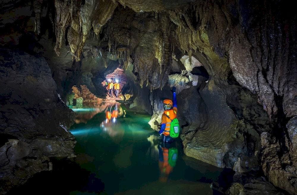Explorers rely on headlamps to navigate narrow passages, underground streams, offering an authentic caving experience (Source: Phong Nha Daily Tours)
